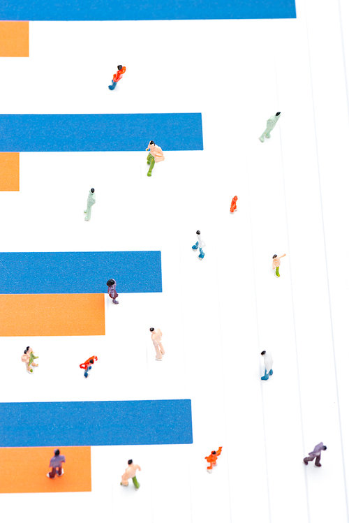 Top view of plastic people figures on surface with blue and orange charts, concept of equality