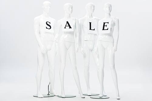 papers with sale lettering on white mannequins isolated on grey