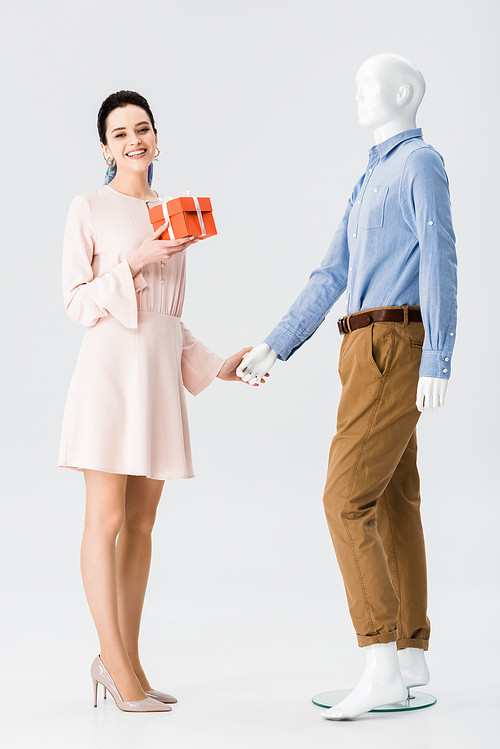 beautiful girl with gift box holding hands with mannequin isolated on grey