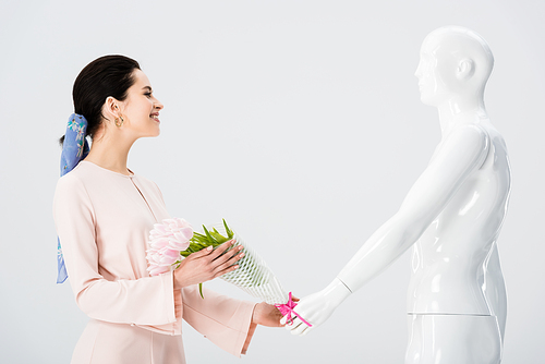 beautiful girl taking flower bouquet from mannequin isolated on grey