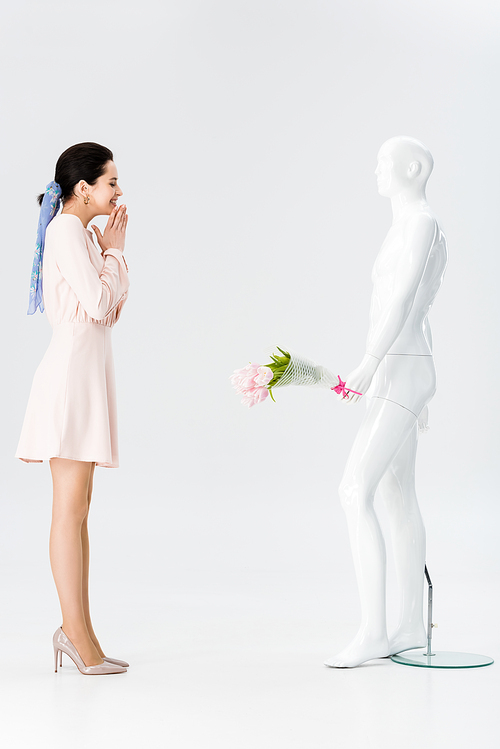 beautiful excited girl and mannequin with flower bouquet isolated on grey