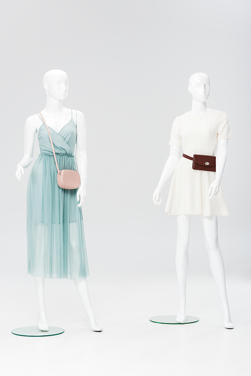 plastic mannequins with bags and dresses isolated on grey