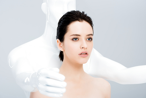 attractive young woman posing with mannequin isolated on grey