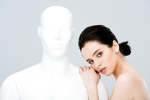 attractive girl posing with mannequin and  isolated on grey