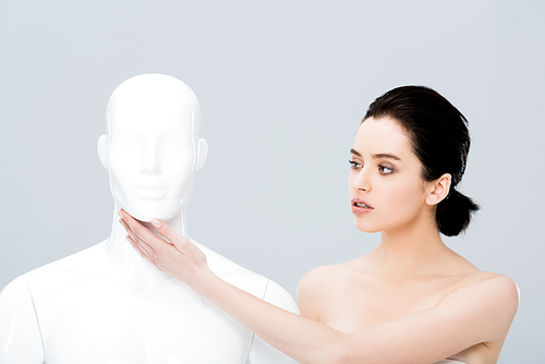 beautiful naked young woman touching mannequin isolated on grey