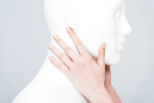 cropped view of girl touching plastic mannequin isolated on grey