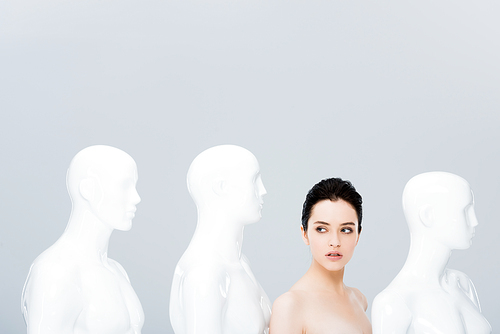 beautiful naked girl near white mannequins isolated on grey