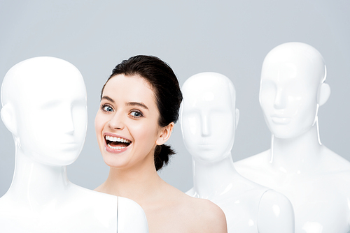 beautiful happy girl posing near mannequins isolated on grey