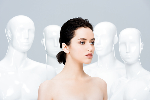 beautiful nude girl posing near mannequins isolated on grey