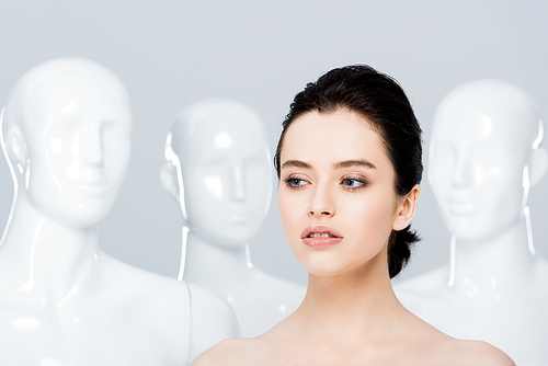 beautiful nude young woman posing with mannequins isolated on grey