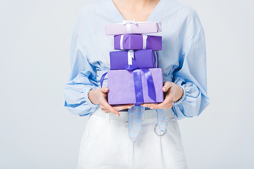 Cropped view of stylish girl holding gift boxes isolated on grey