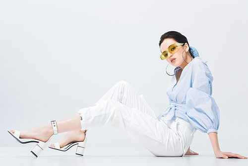 beautiful stylish girl in sunglasses sitting and posing on grey