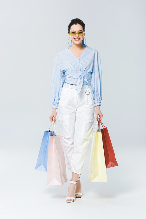 beautiful smiling girl with shopping bags  on grey