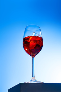 low angle view of cocktail Aperol Spritz with ice cube in glass on blue background