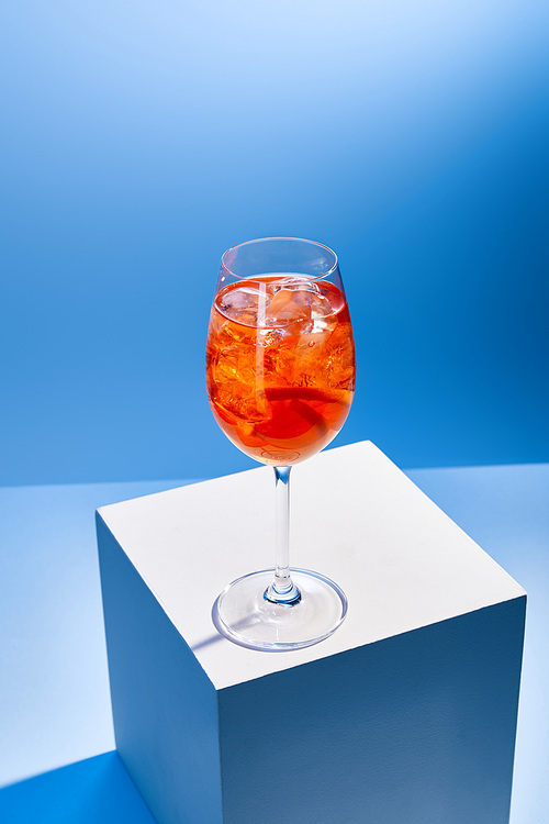 cocktail Aperol Spritz with ice cubes in glass on blue background
