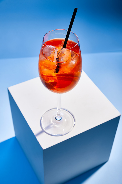 high angle view of cocktail Aperol Spritz with straw in glass on blue background