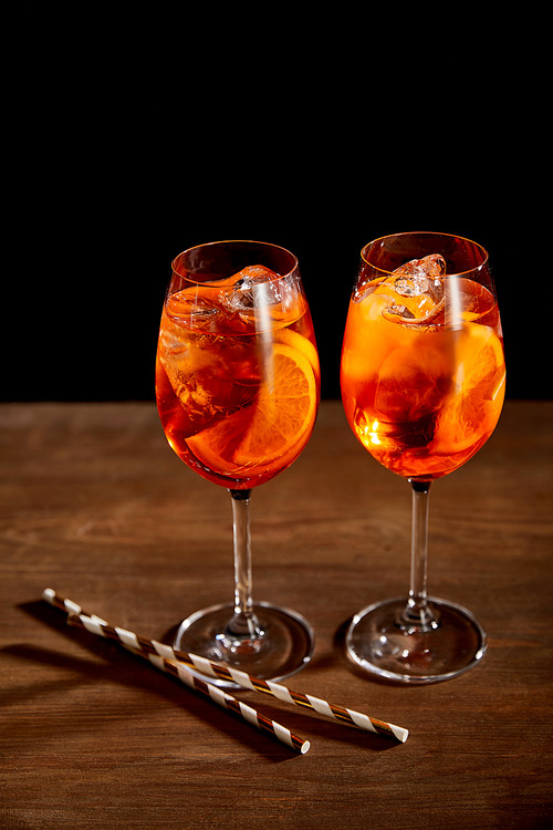Aperol Spritz in glasses with straws on wooden table