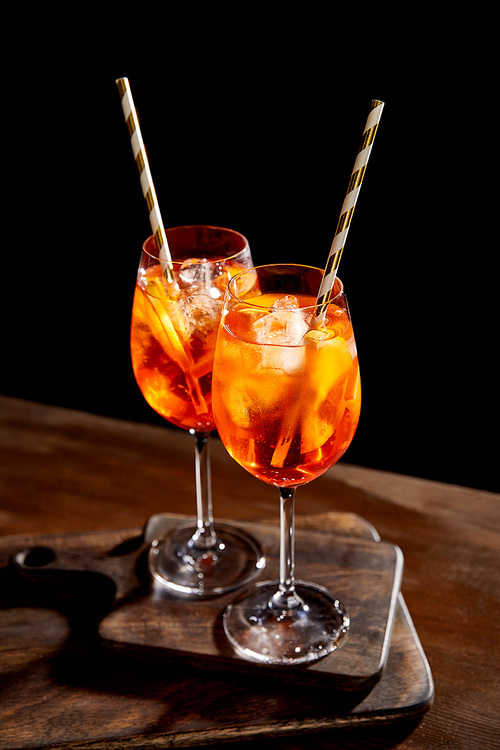 Aperol Spritz in glasses with straws on wooden chopping boards
