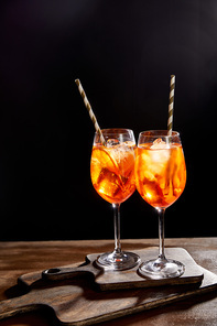 Aperol Spritz in glasses with straws on chopping boards