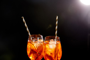 Aperol Spritz in glasses with straws on black background