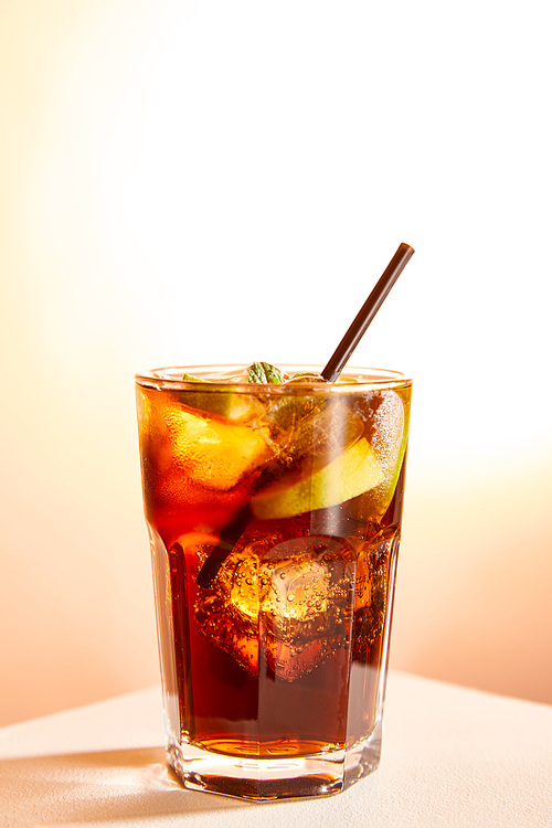 cocktail cuba libre in glass with straw on beige background