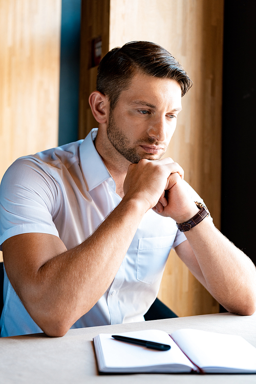 pensive muscular man sitting with clenched hands in cafe