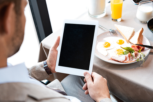 cropped view of businessman holding digital tablet with blank screen in cafe