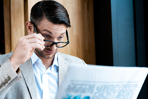surprised businessman in glasses reading newspaper in cafe