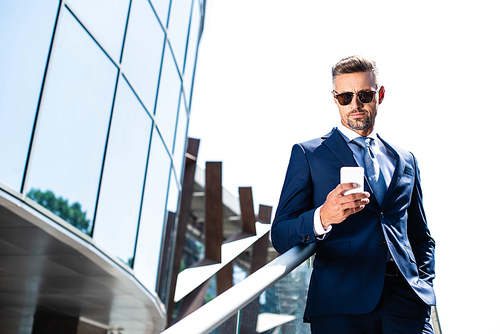 handsome man in suit with hand in pocket using smartphone