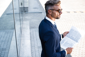 high angle view of handsome man in suit and glasses holding newspaper