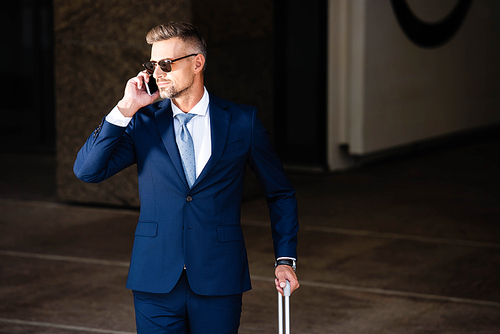 handsome businessman in suit and glasses talking on smartphone