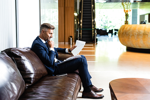 side view of handsome businessman in suit looking at papers