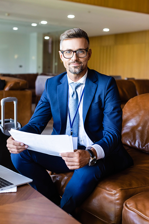 handsome businessman in formal wear and glasses holding documents
