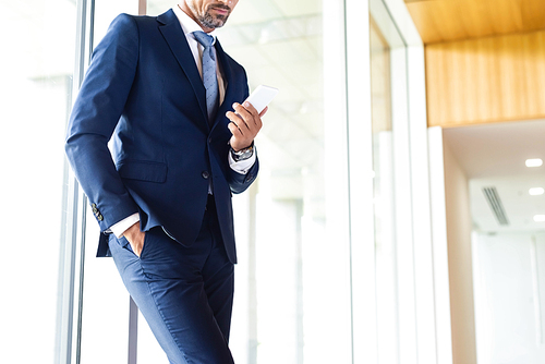 cropped view of businessman in suit with hand in pocket using smartphone