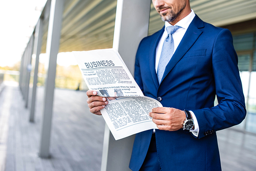 cropped view of businessman in formal wear reading newspaper business