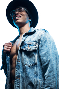 low angle view of handsome mixed race man in denim and hat smiling isolated on white