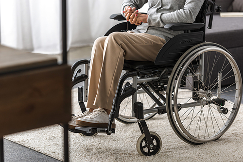 partial view of disabled senior woman in wheelchair at home