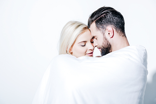 beautiful girlfriend and handsome boyfriend covered in blanket on white