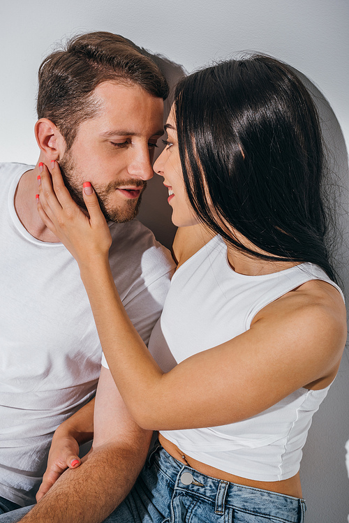 young couple in love sitting on floor, smiling and trying to kiss each other