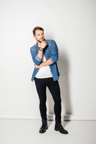 full length view of young man in stylish clothes posing and looking away