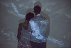 back view of couple standing in dark room and hugging each other