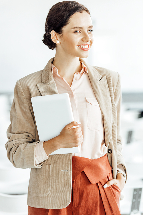attractive businesswoman in formal wear smiling and holding digital tablet