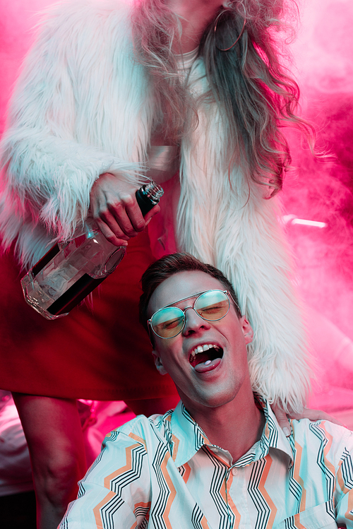 girl with alcohol near man in sunglasses with lsd on tongue in nightclub