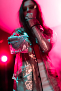 girl holding plastic zipper bag with drugs in nightclub, selective focus