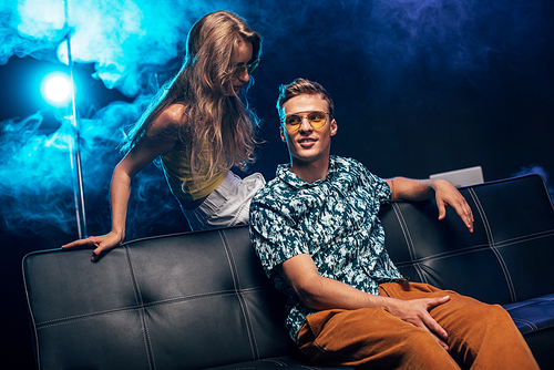 man and young woman siting on couch during rave party in nightclub