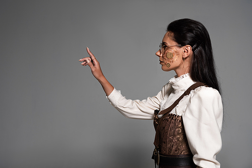 side view of steampunk young woman in white blouse gesturing on grey