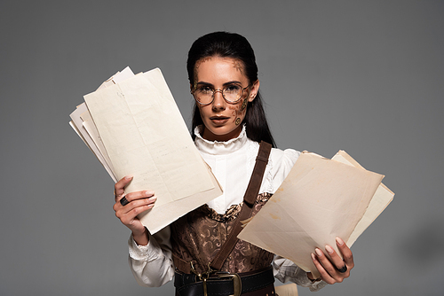 attractive steampunk woman in glasses holding documents and  on grey