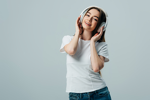 happy pretty girl listening music in wireless headphones isolated on grey
