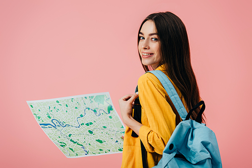 beautiful smiling girl with backpack holding  map isolated on pink