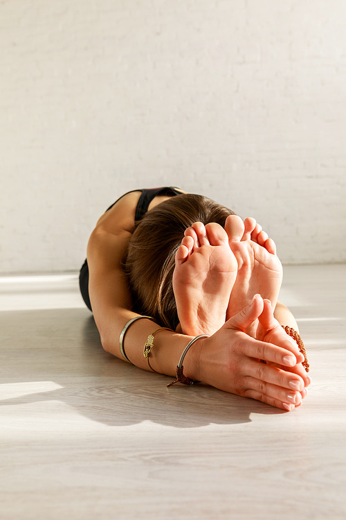 flexible woman with barefoot stretching on floor